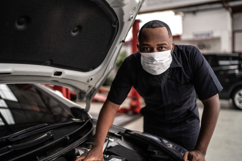 Portrait of auto mechanic man with face mask at auto repair shop