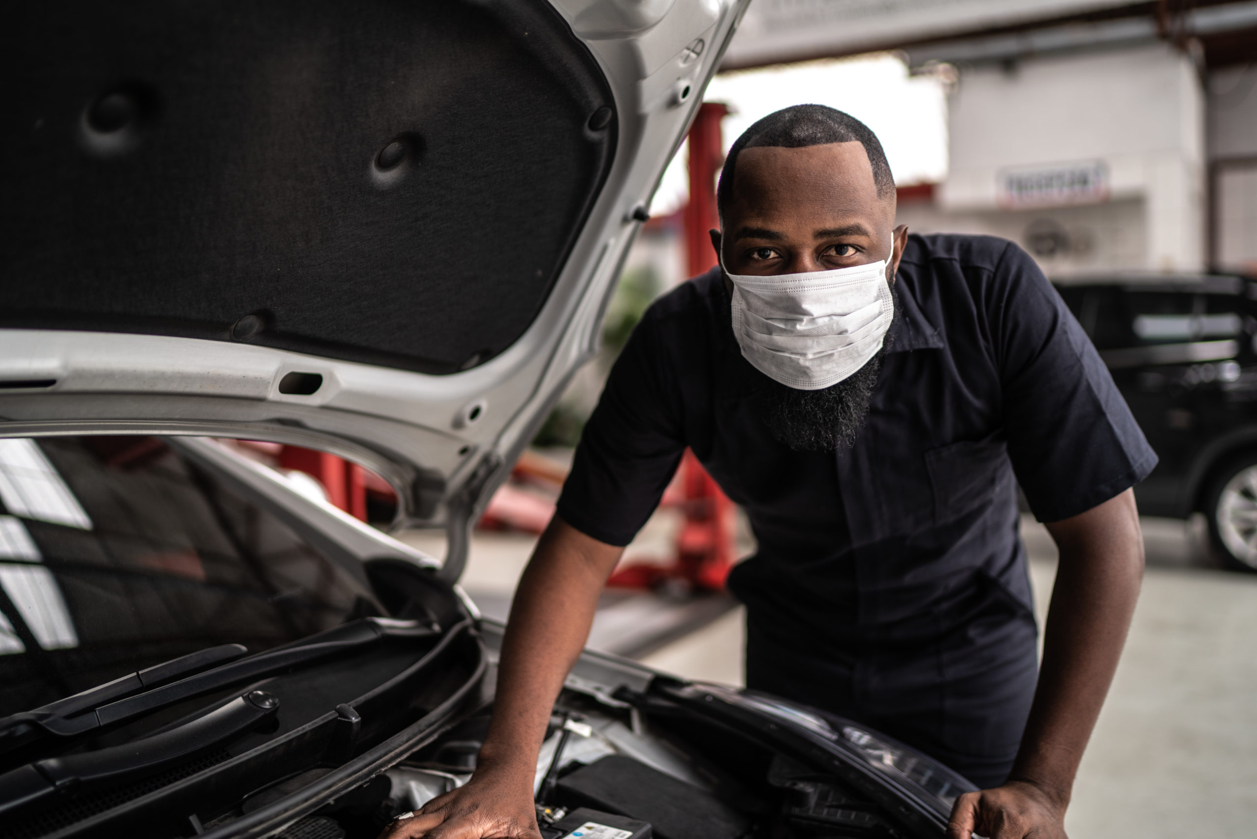 Portrait of auto mechanic man with face mask at auto repair shop