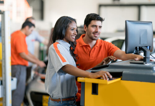 Mechanics working together at an auto repair shop using a computer