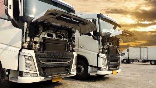 White semi trucks an opening front the engine parking at sunset sky, freight industry logistics transport.
