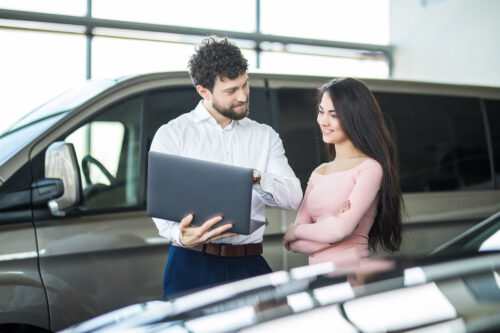 Sales manager showing something on a laptop to the smiling woman customer