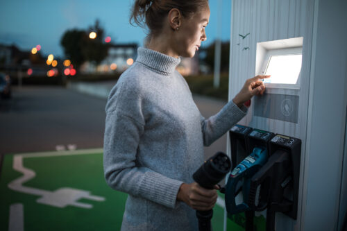 Young woman charging an electric vehicle