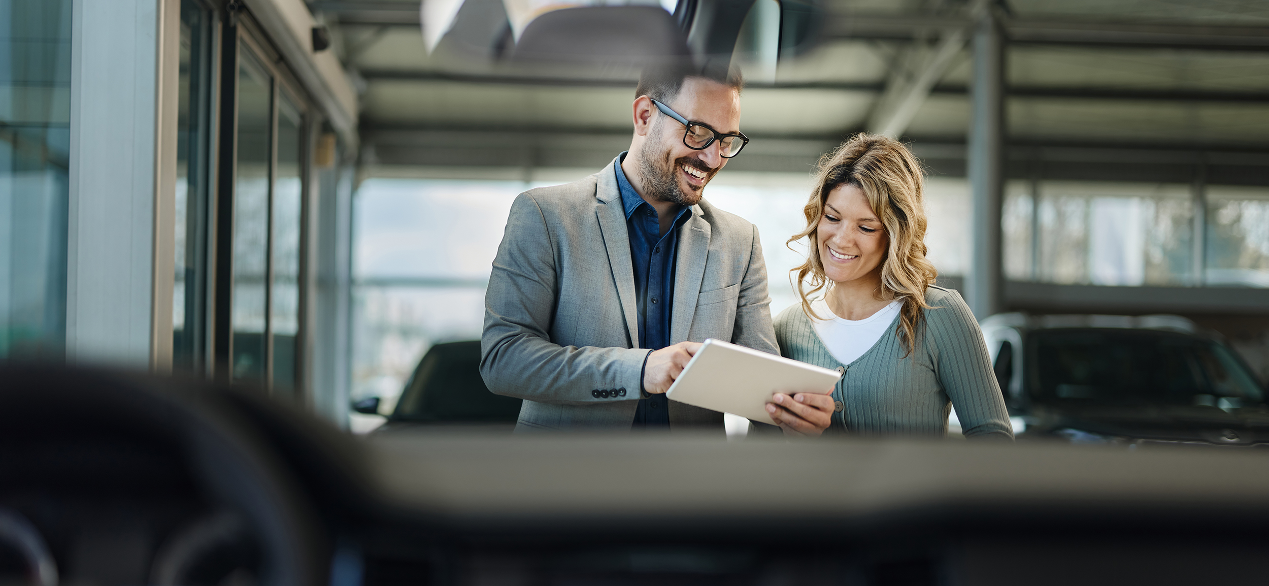 Happy salesman and his customer using touchpad in a showroom.