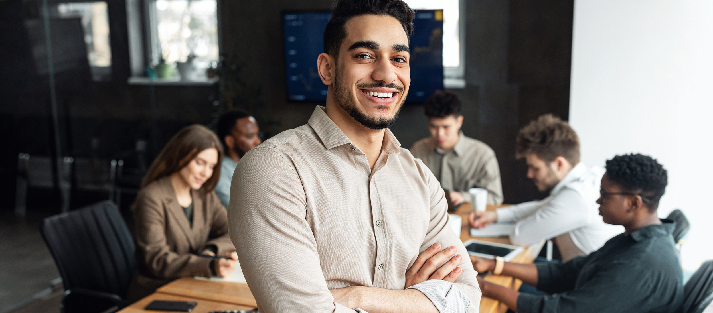 Young bearded businessman sitting on desk and posing