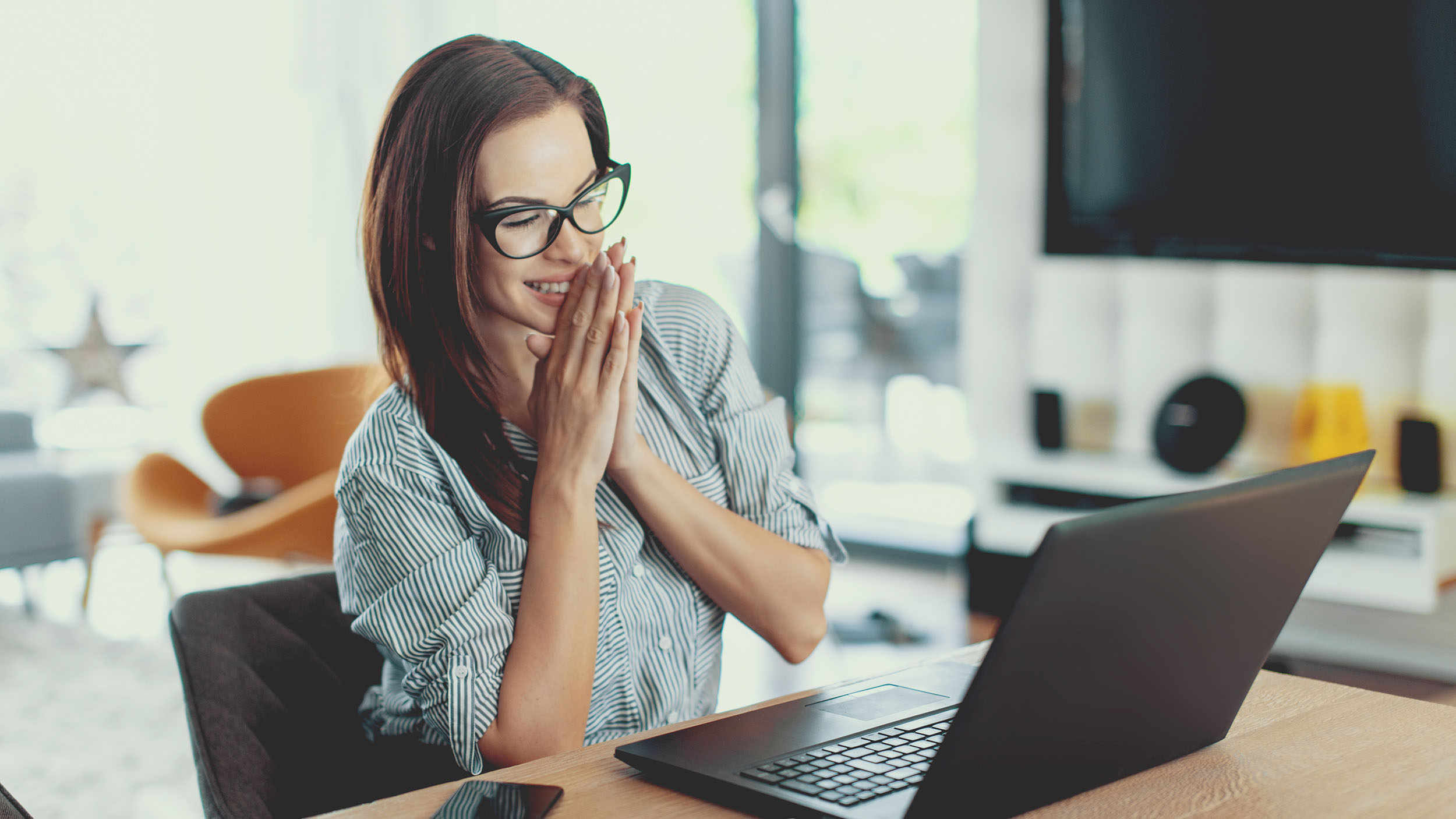 Happy young modern businesswoman reading good news on laptop