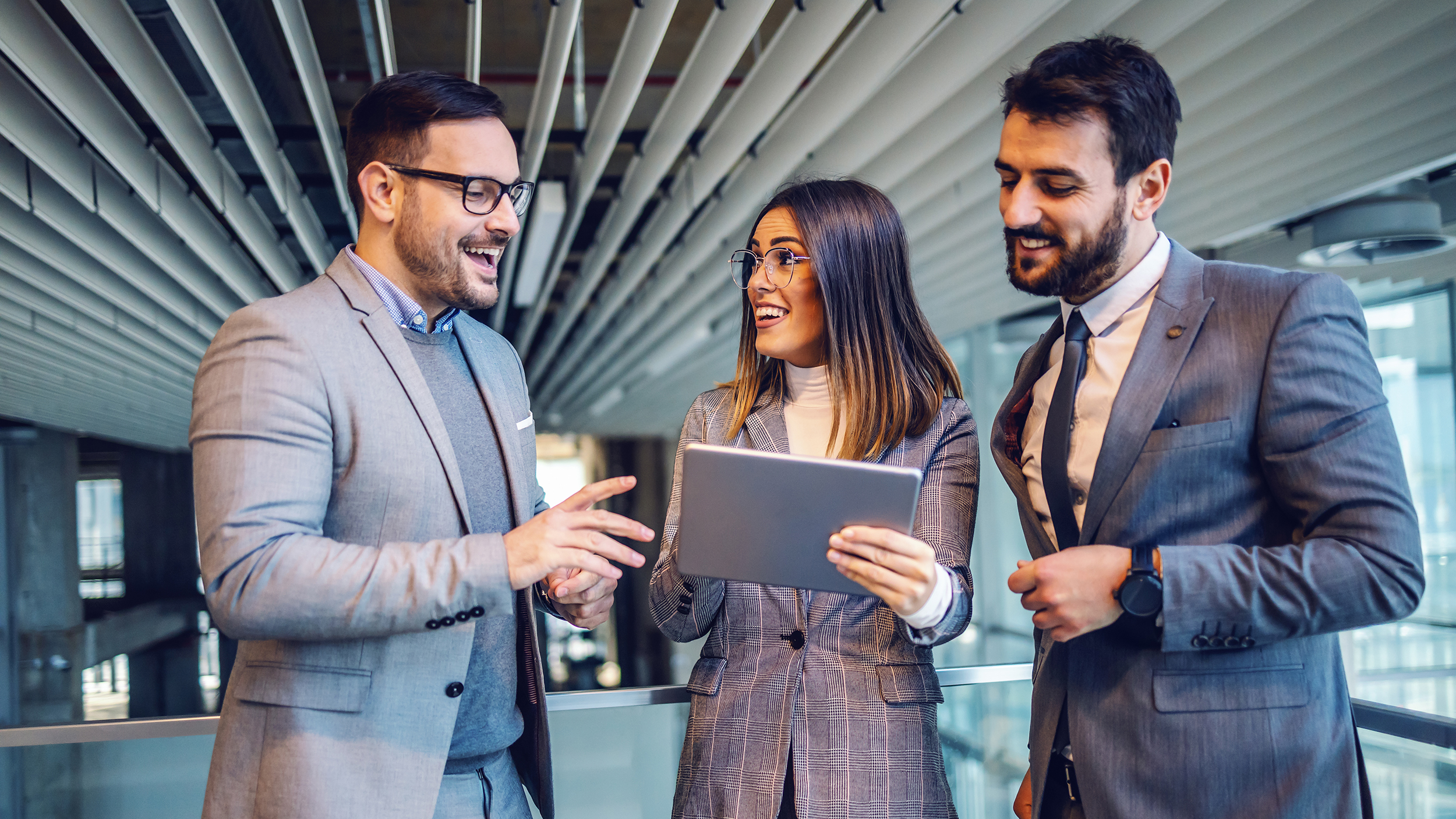 Group of elegant dressed successful real estate agents standing in the building in construction process and putting property on auction. Woman in the middle holding tablet.