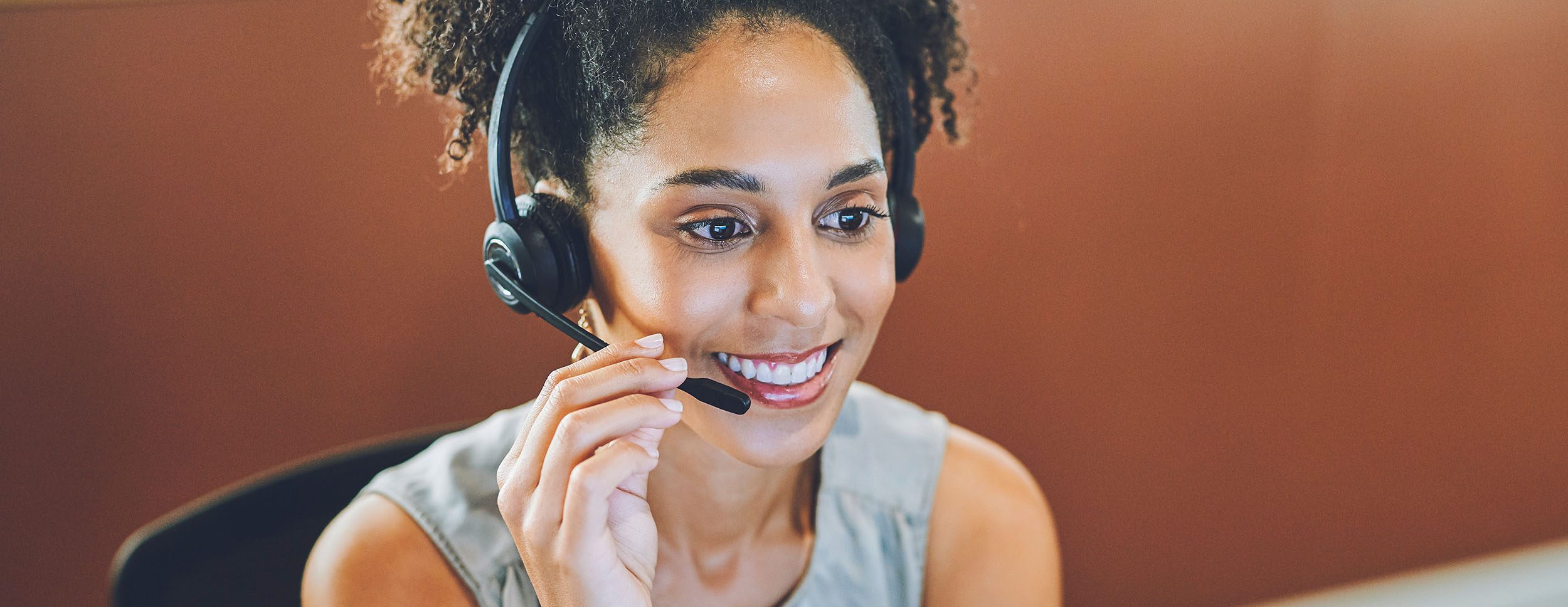 Smiling, helping and working customer support service worker with a headset and office computer. Call center worker on a online internet consulting call. Telephone operator agent giving web advice