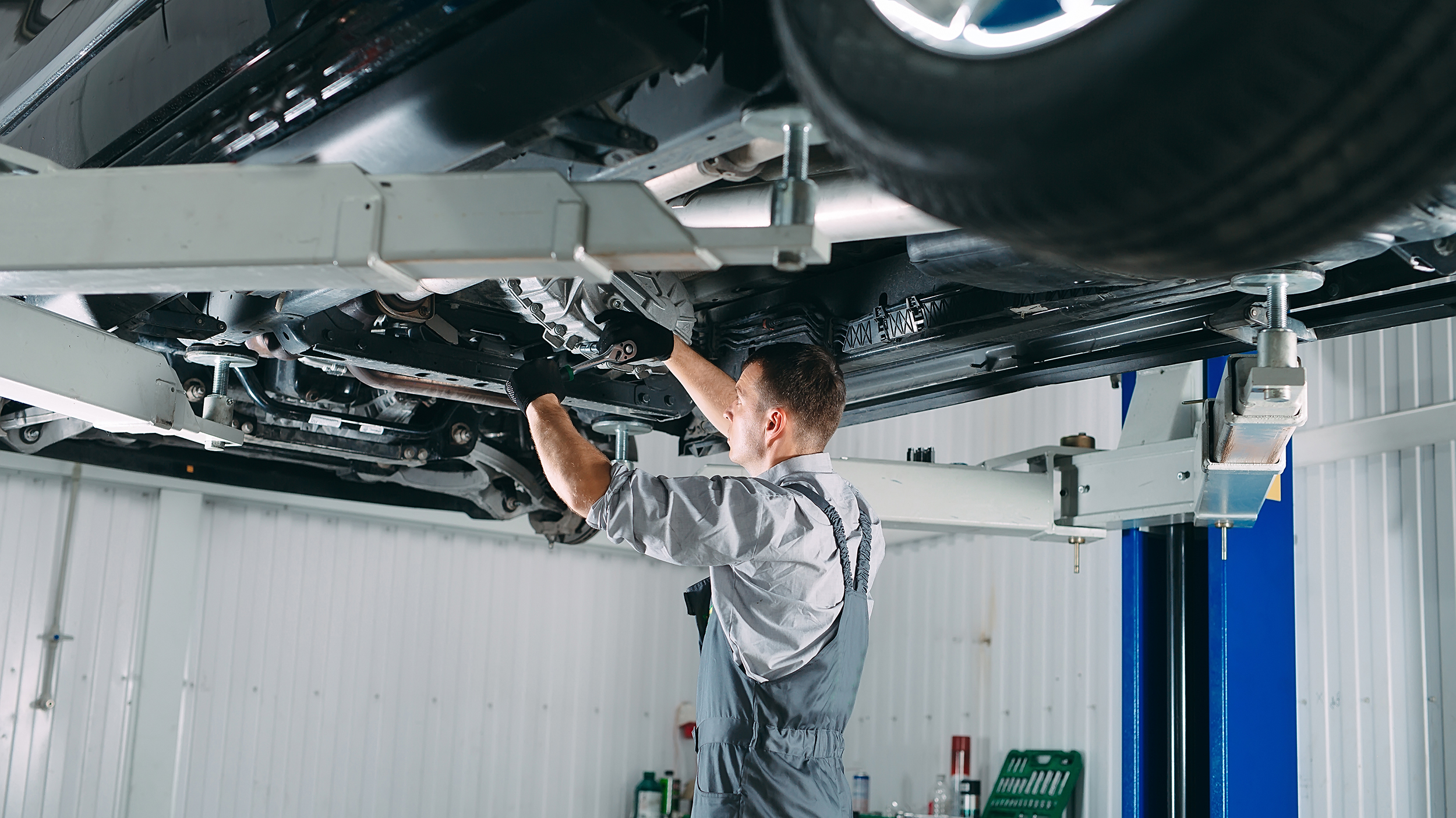 Portrait of a mechanic repairing a lifted car.