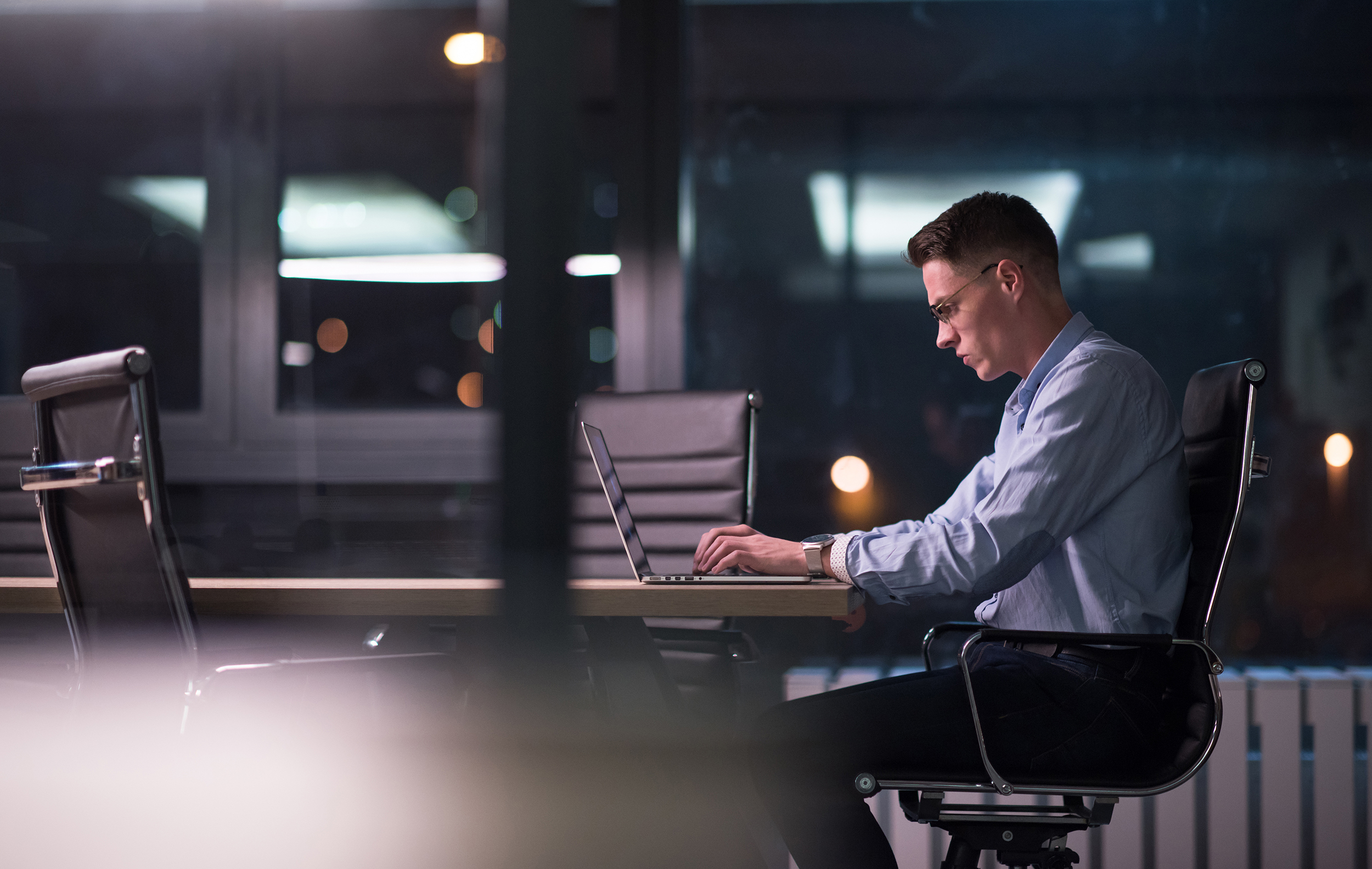 man working on laptop in dark office