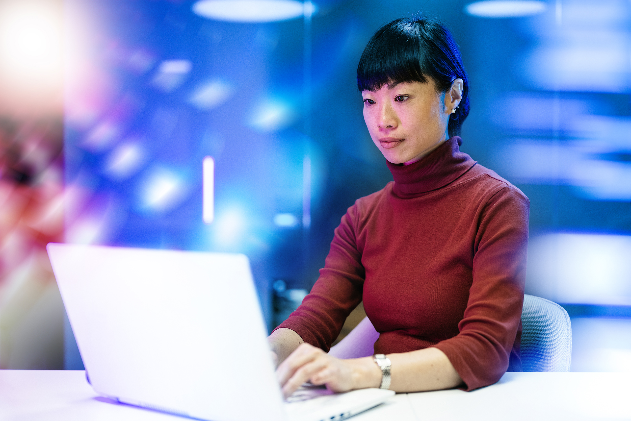 Futuristic office with Japanese mature businesswoman working on laptop