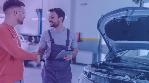 Young man shaking hands with car mechanic