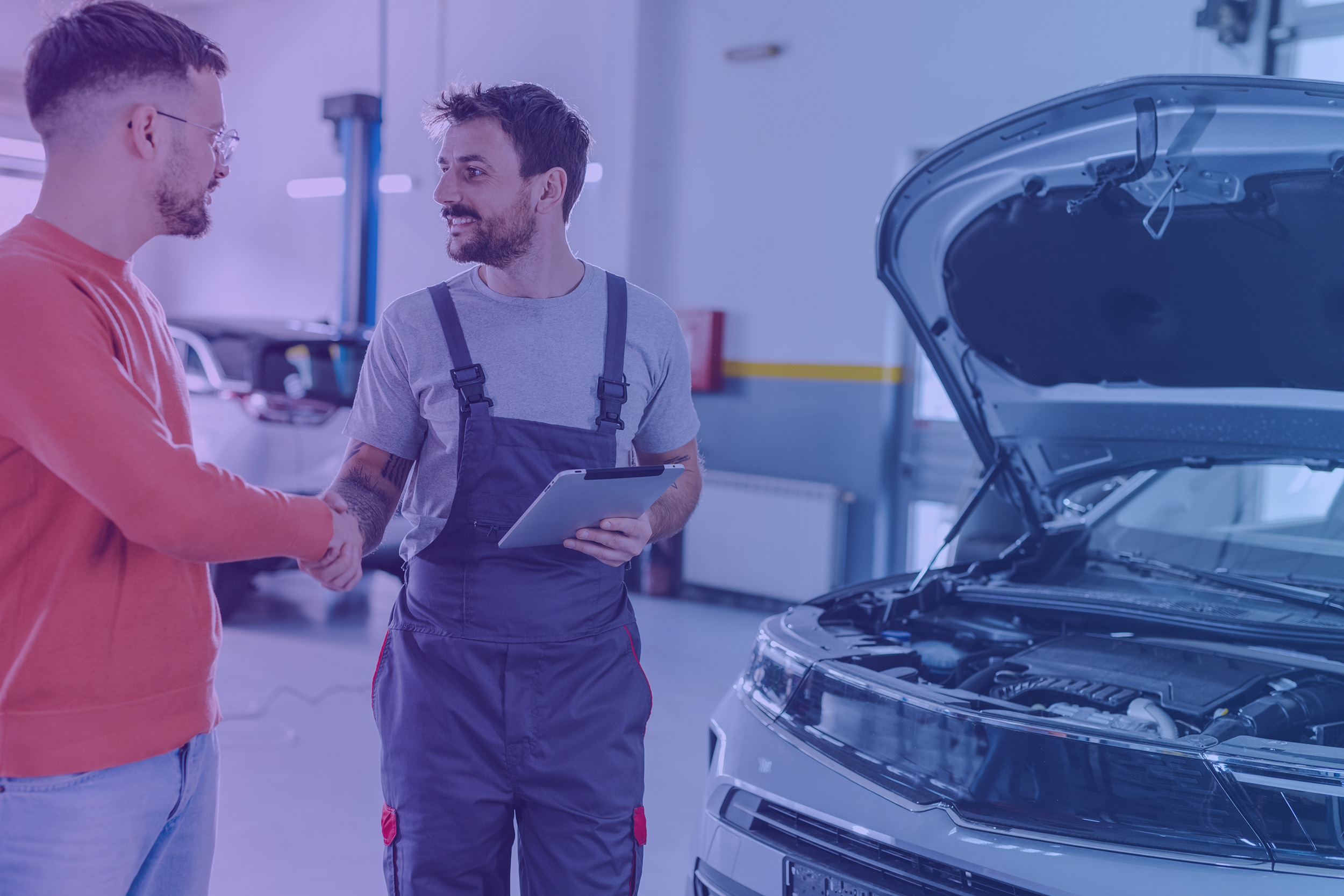 Young man shaking hands with car mechanic